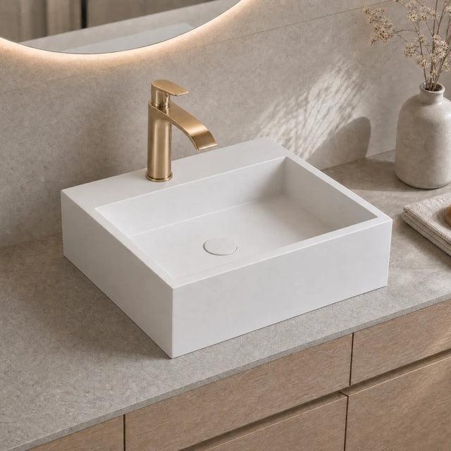 White rectangular sink with gold faucet on a beige countertop