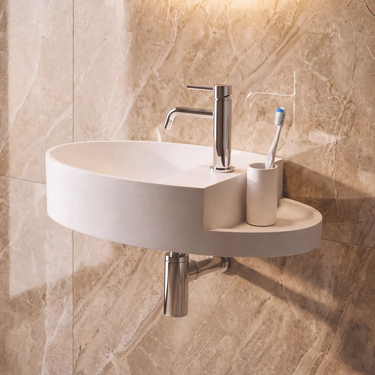 A modern wall-mounted oval bathroom sink in white, paired with a polished chrome faucet, toothbrush holder, and toothbrush, set against a beige marble-look tiled wall.