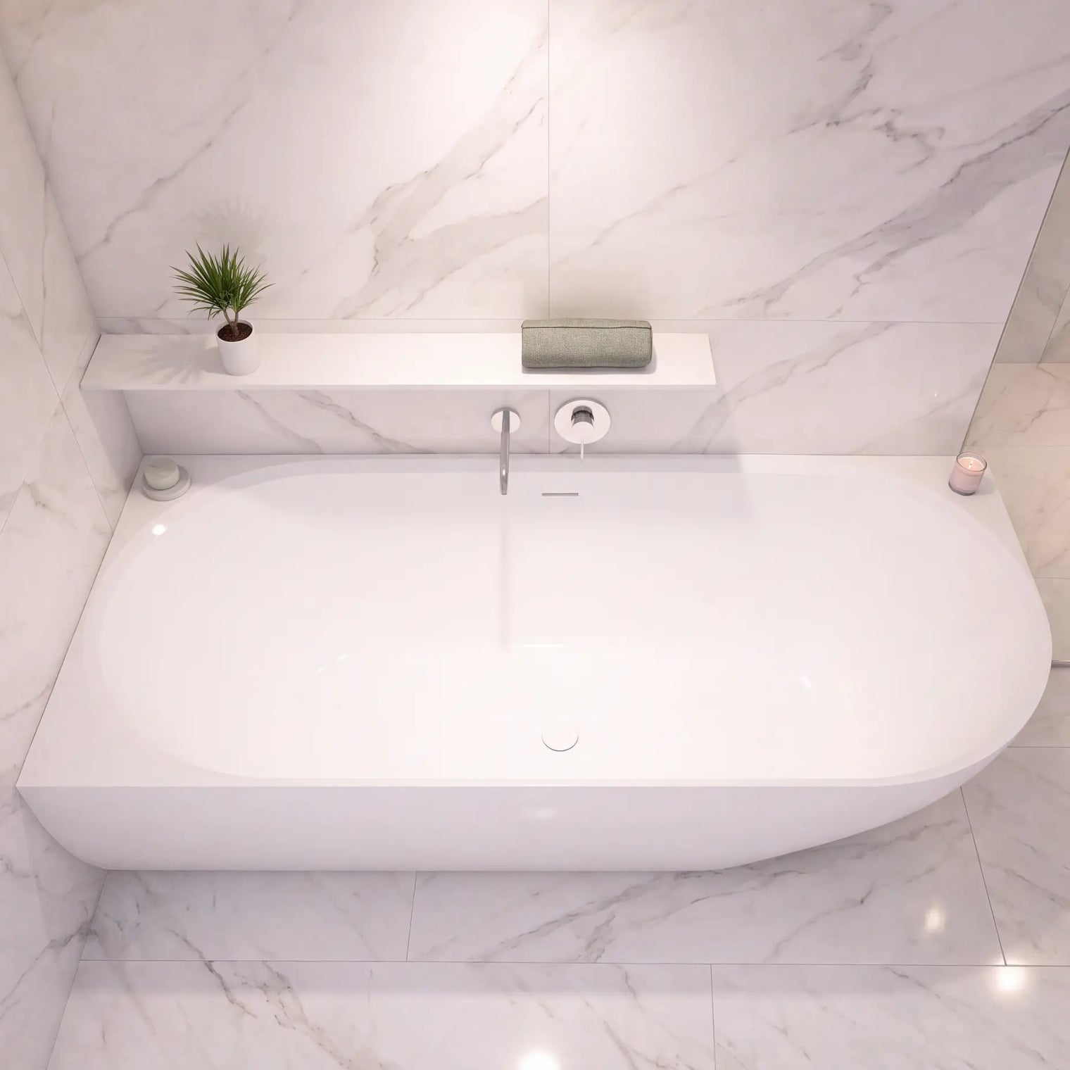 A modern white freestanding bathtub set into a light marble bathroom with a matching marble surround, a small shelf with a plant and soap, and a chrome faucet.