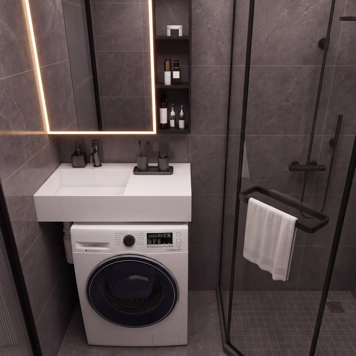A modern bathroom scene featuring a white wall-mounted sink and washing machine combo, a black-framed glass shower enclosure, dark gray stone-look tiles, and a lit mirror.