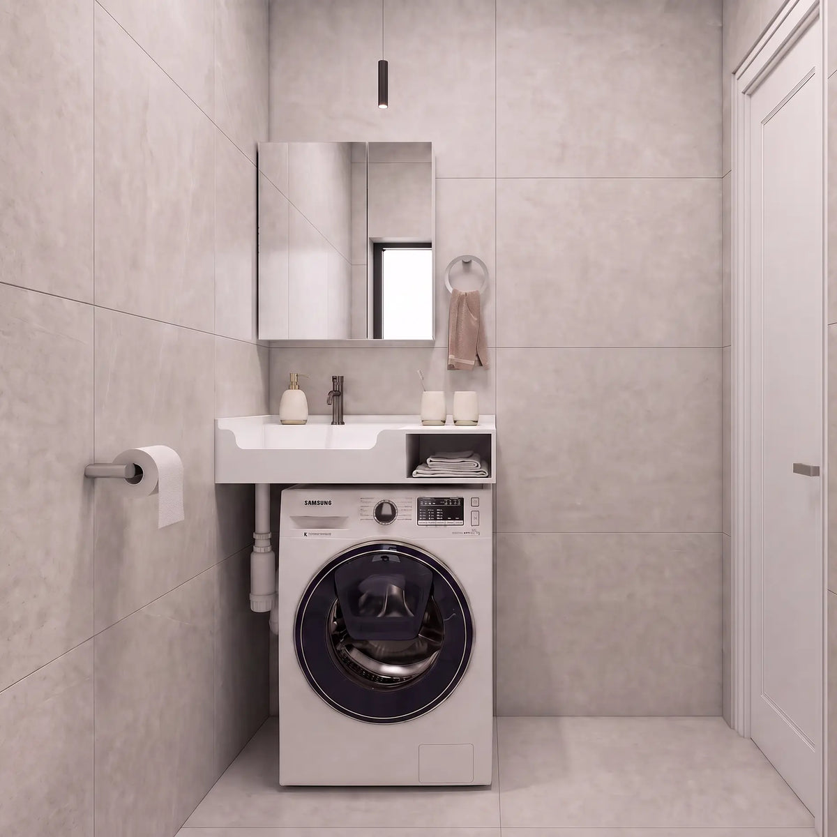 A compact bathroom setup featuring a white front-loading washing machine integrated beneath a matching white sink and mirror, set against light gray tiled walls and floor.