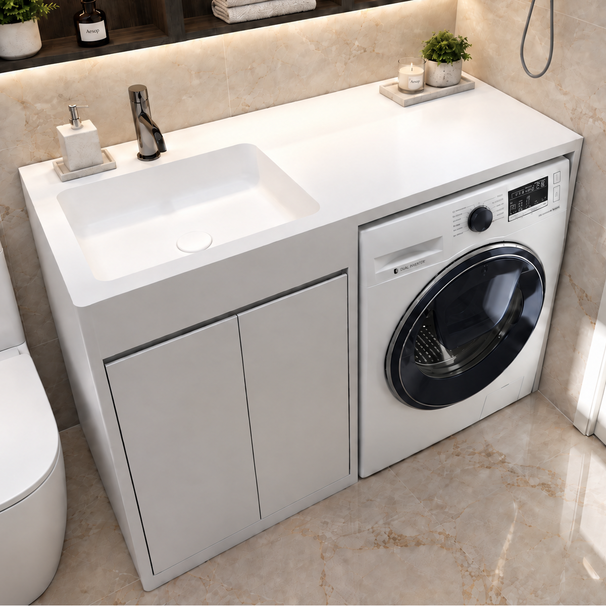 A modern bathroom vanity unit with an integrated white sink and a front-loading washing machine, set against beige marble-look tiled walls. A white toilet is visible on the left, and a white door is on the right.