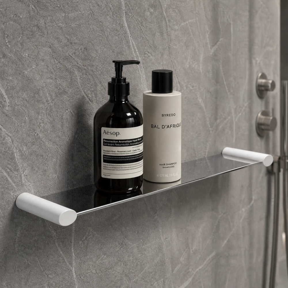 Bathroom shelf with Aesop products against a gray tiled wall.