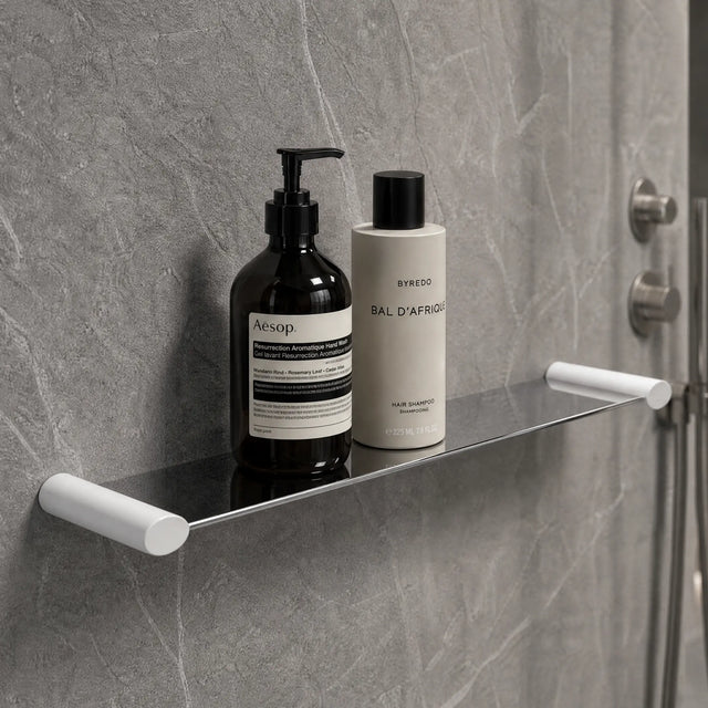 Bathroom shelf with Aesop products against a gray tiled wall.