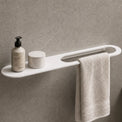 Bathroom setup with a shelf, towel, and toiletries against a gray wall.