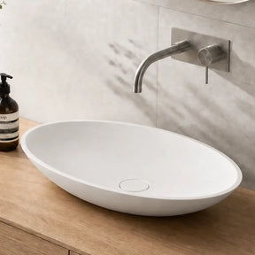 Bathroom vanity with a white sink, wooden cabinet, and decorative items.