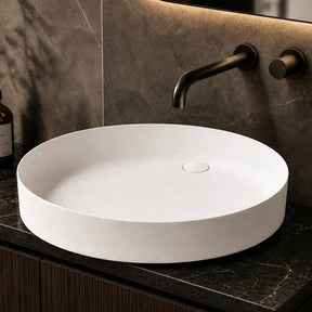 White round sink on a dark marble countertop with a modern faucet and decorative elements.