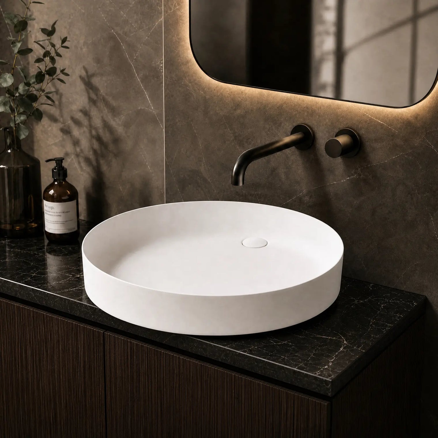 White round sink on a dark marble countertop with a modern faucet and decorative elements.