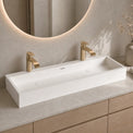 Bathroom vanity with white rectangular sink, gold faucets, and decorative elements.