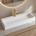 Modern bathroom vanity with a white sink and gold faucet.