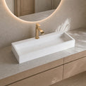 Modern bathroom vanity with a white sink and gold faucet.