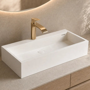 White rectangular sink with gold faucet on a beige countertop