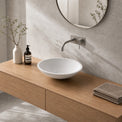 Bathroom vanity with wooden cabinet, white sink, and decorative items.