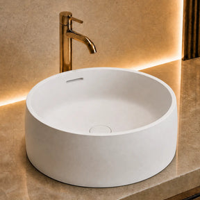 Modern bathroom vanity with a white solid surfaces sink and gold faucet.