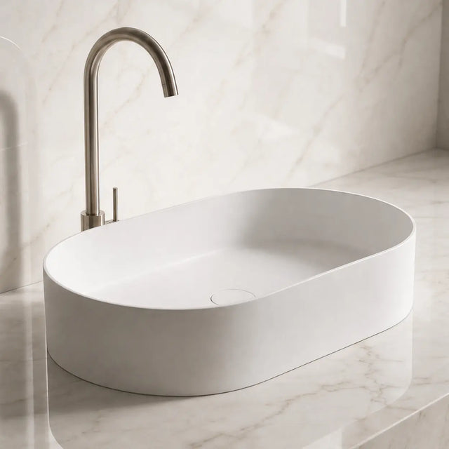 White Solid Surfaces oval sink on a marble countertop with a matching wall.