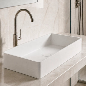 Modern bathroom with a white sink and bronze faucet against a marble wall.