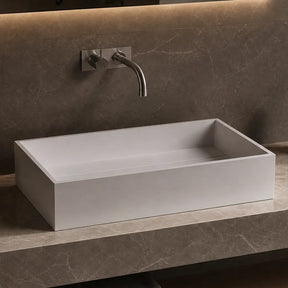 Bathroom vanity with a rectangular solid surfaces sink, faucet, and minimal decor.