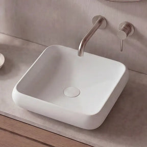 Bathroom vanity with a square sink, faucet, and decorative items.