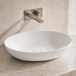 White ceramic sink on a marble countertop with a matching wall-mounted faucet.