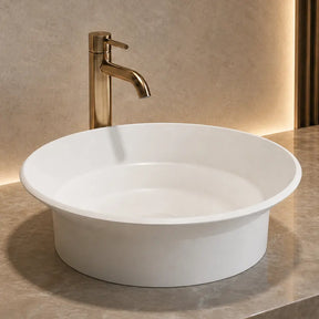 White round Solid surfaces sink with gold faucet on a marble countertop in a bathroom setting.