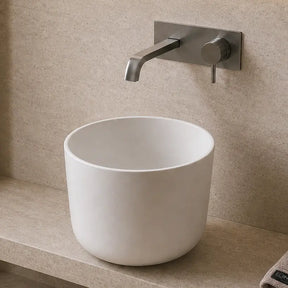 Modern bathroom with a white Solid Surfaces sink, towel, and decorative elements.
