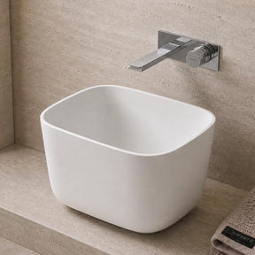 Modern bathroom with a white freestanding Solid Surfaces sink, faucet, and decorative elements.
