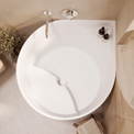 A top-down view of a white corner bathtub with a chrome faucet and drain, styled in a warm beige bathroom with plants and wooden accents.