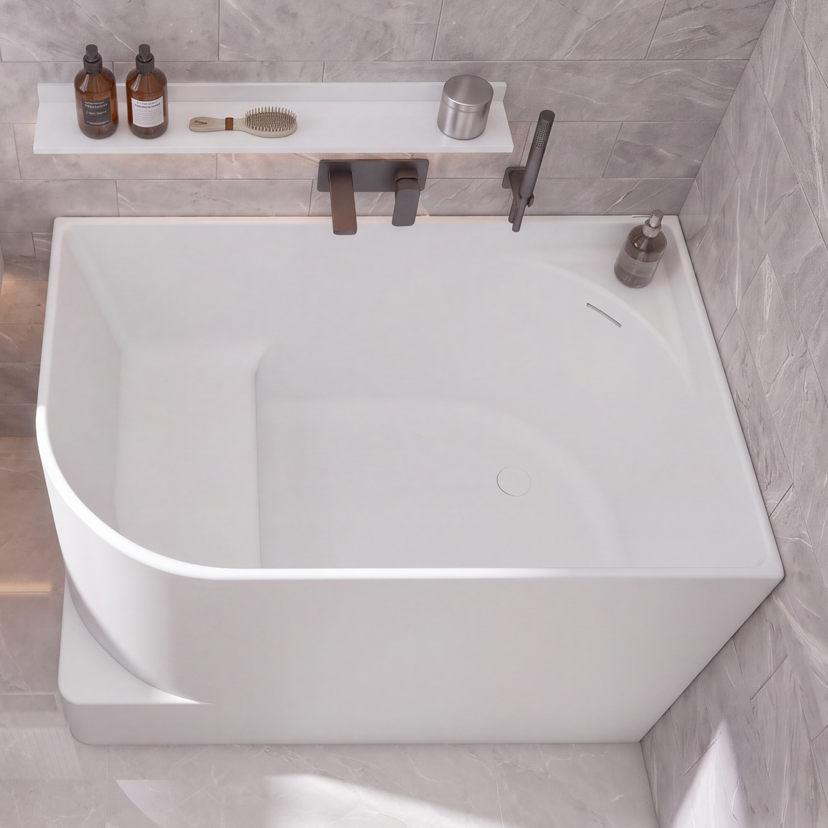A modern bathroom scene with a large white freestanding bathtub, a white wall-mounted sink, gray stone tile walls and floor, and a few small bathroom accessories and towels.