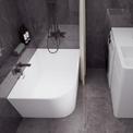 A modern bathroom setup featuring a white freestanding bathtub with a dark wall-mounted faucet and shower system, alongside a white sink vanity with a matching dark faucet and a small washing machine, all set against dark gray tiled walls and floor.