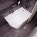 A modern white freestanding bathtub with a dark gray tiled bathroom setting, featuring a wall-mounted chrome faucet, a handheld shower attachment, and a beige curtain on the left.