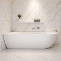 A modern freestanding bathtub in a bright marble-look bathroom with a glass shower enclosure, recessed lighting, and built-in shelving.