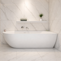 A modern freestanding bathtub in a bright marble-look bathroom with a glass shower enclosure, recessed lighting, and built-in shelf details.