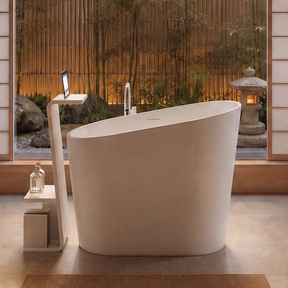 A modern freestanding oval bathtub in a minimalist, warm-toned bathroom with wood walls, dual pedestal sinks, a glass shower enclosure, and a large window overlooking bamboo.