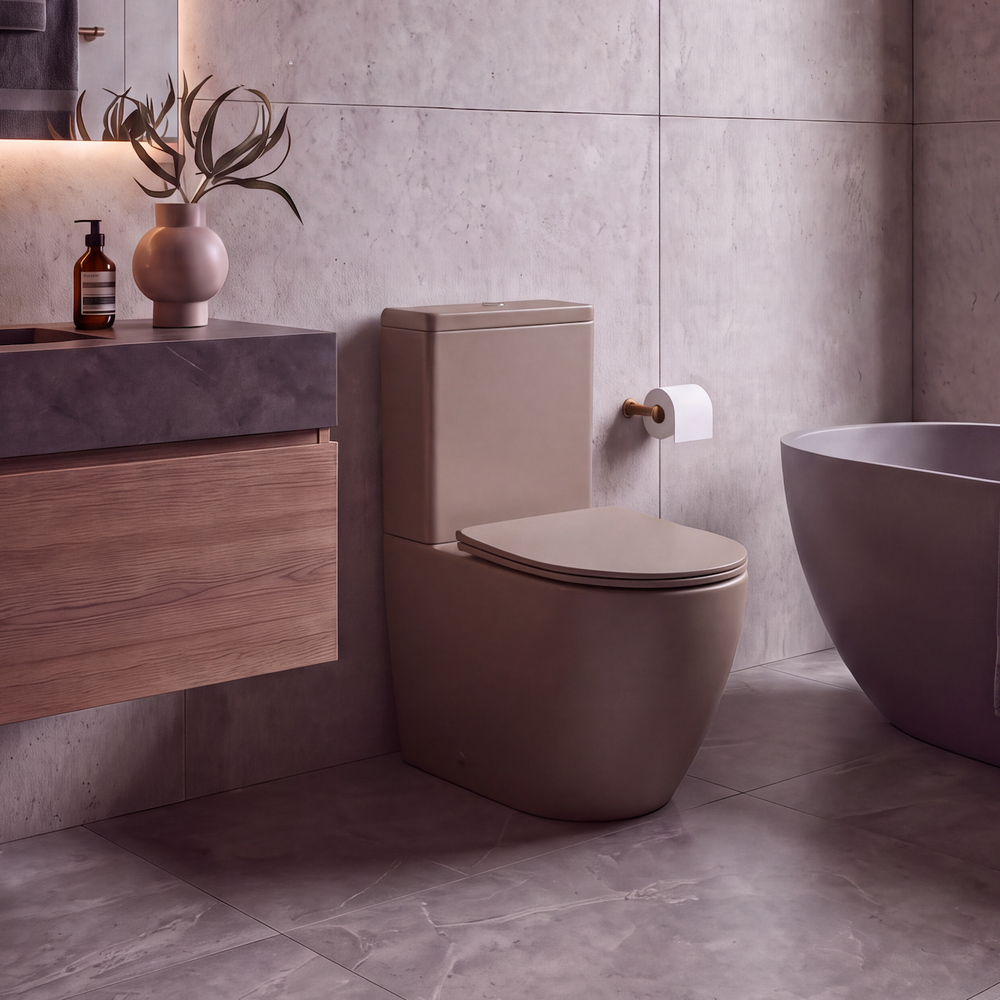 A modern bathroom interior featuring a matte taupe ceramic toilet, a floating wooden vanity with a dark stone sink, a freestanding bathtub, and large textured gray stone tiles.