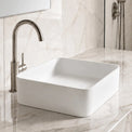 White Solid Surfaces rectangular sink on a marble countertop with a silver faucet.