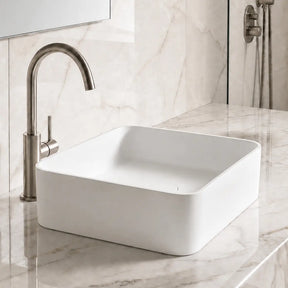 White Solid Surfaces rectangular sink on a marble countertop with a silver faucet.