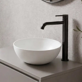 Modern bathroom with a floating vanity, round mirror, and plant.