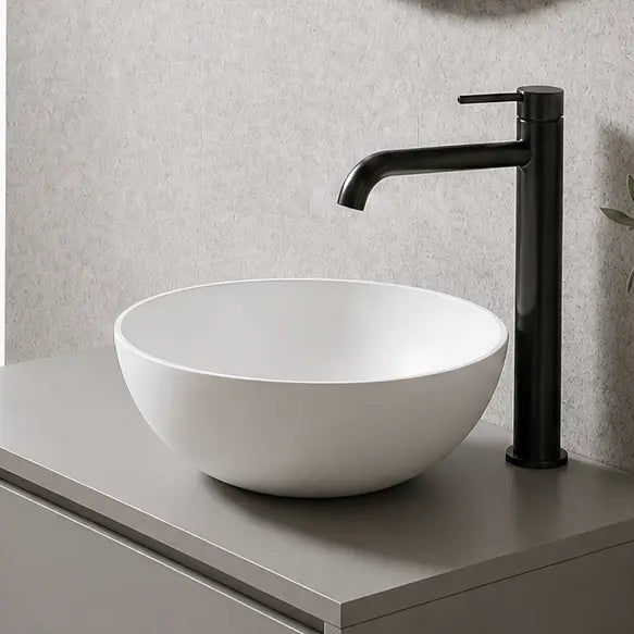 Modern bathroom with a floating vanity, round mirror, and plant.