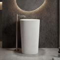 White freestanding sink in a modern bathroom setting with a circular mirror and neutral color palette.