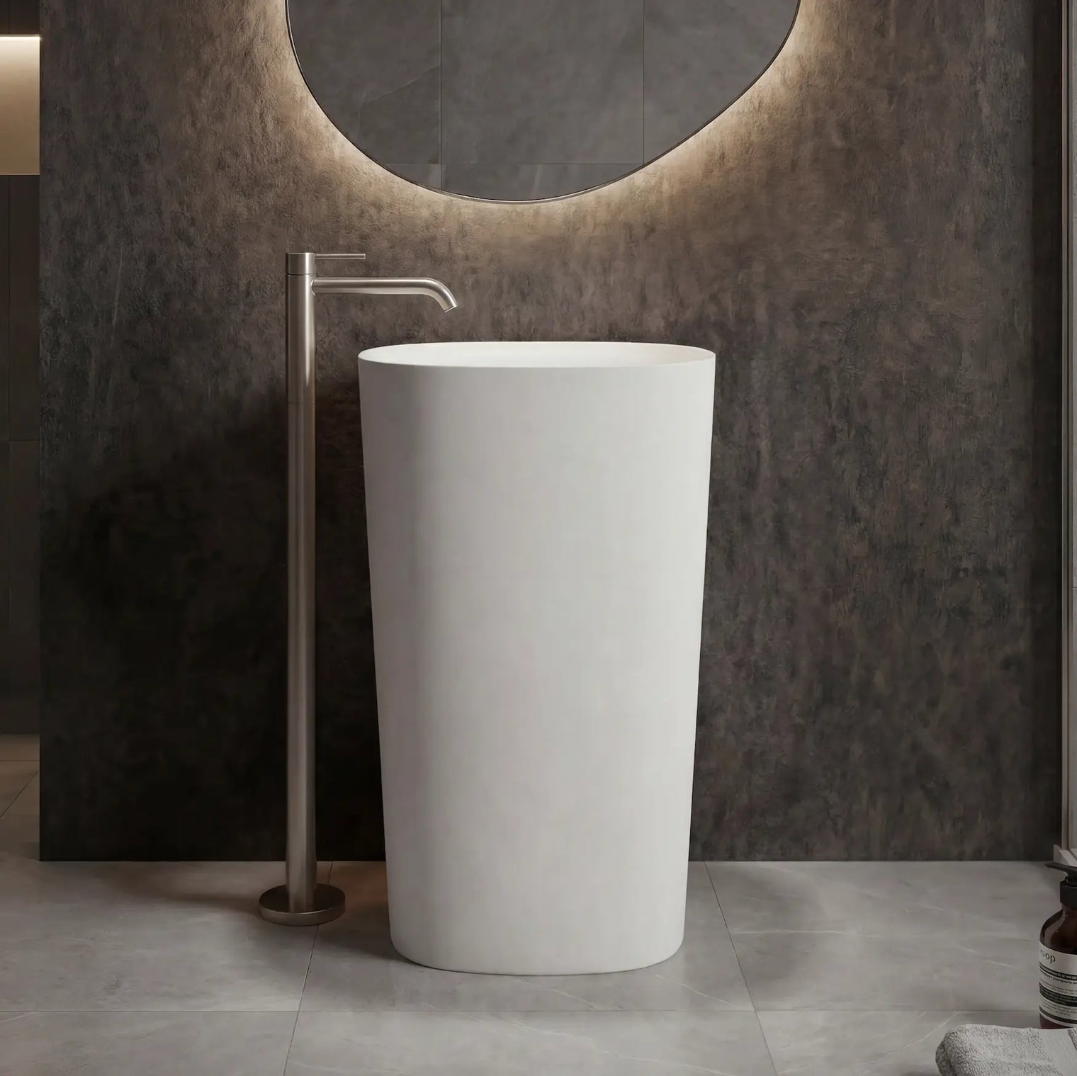 White freestanding sink in a modern bathroom setting with a circular mirror and neutral color palette.