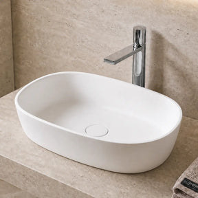 Modern bathroom solid surfaces sink with faucet, towel, and plant in a neutral-toned setting