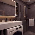 A modern bathroom interior with dark gray tiled walls, a white countertop and sink, a glass shower enclosure, a white washing machine, and part of a white toilet visible.
