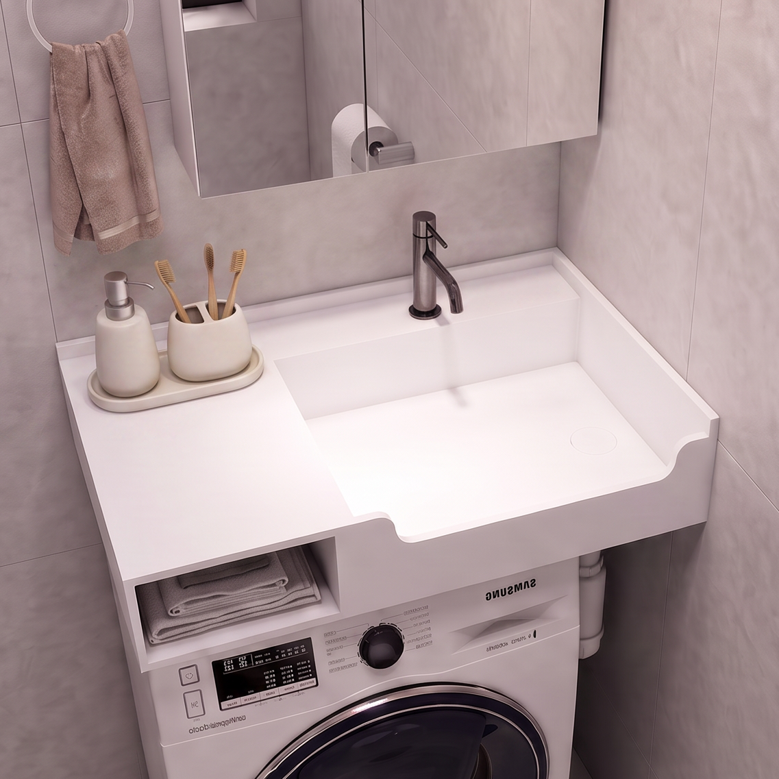 A compact bathroom vanity setup with a white sink and countertop, integrated washing machine underneath, shown in a tiled bathroom. A mirror, faucet, soap dispenser, and toilet paper holder are visible.