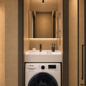 A modern bathroom setup featuring a Samsung washing machine integrated beneath a white double-sink vanity with a large mirror and warm ambient lighting.