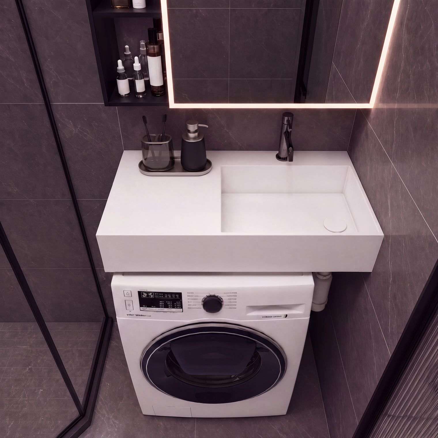A modern bathroom setup featuring a white rectangular sink countertop with a matte black faucet, integrated into a white front-loading washing machine. The unit is set against dark gray tiled walls under a black-framed mirror with warm lighting.