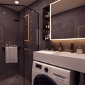 A modern bathroom interior with dark gray tiled walls, a white countertop and sink, a glass shower enclosure, a white washing machine, and part of a white toilet visible.