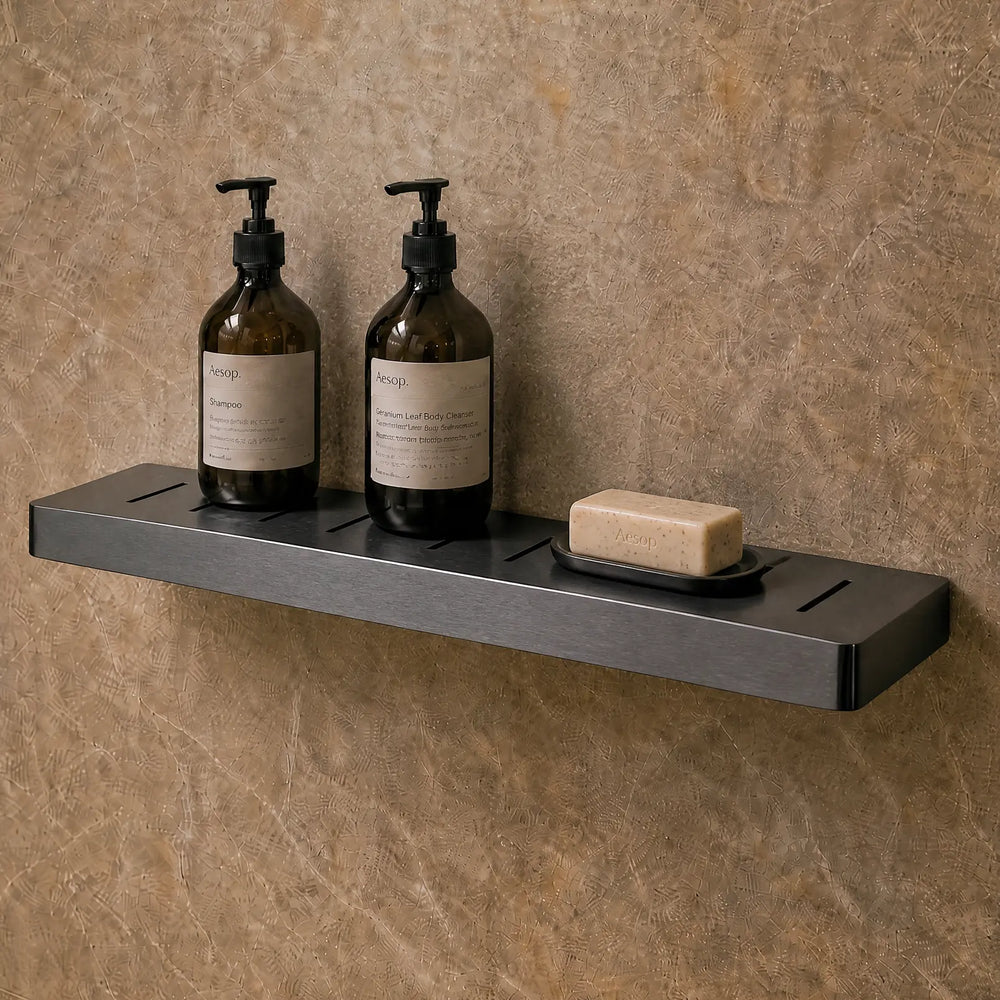 Bathroom with shower setup, bottles on a shelf, and mirror reflecting the room.
