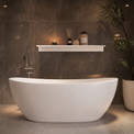 A modern freestanding oval bathtub in matte white, set against a dark brown tiled wall with a floating shelf holding candles and toiletries, and a potted plant to the right.